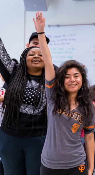 Female students raising hands enthusiastically